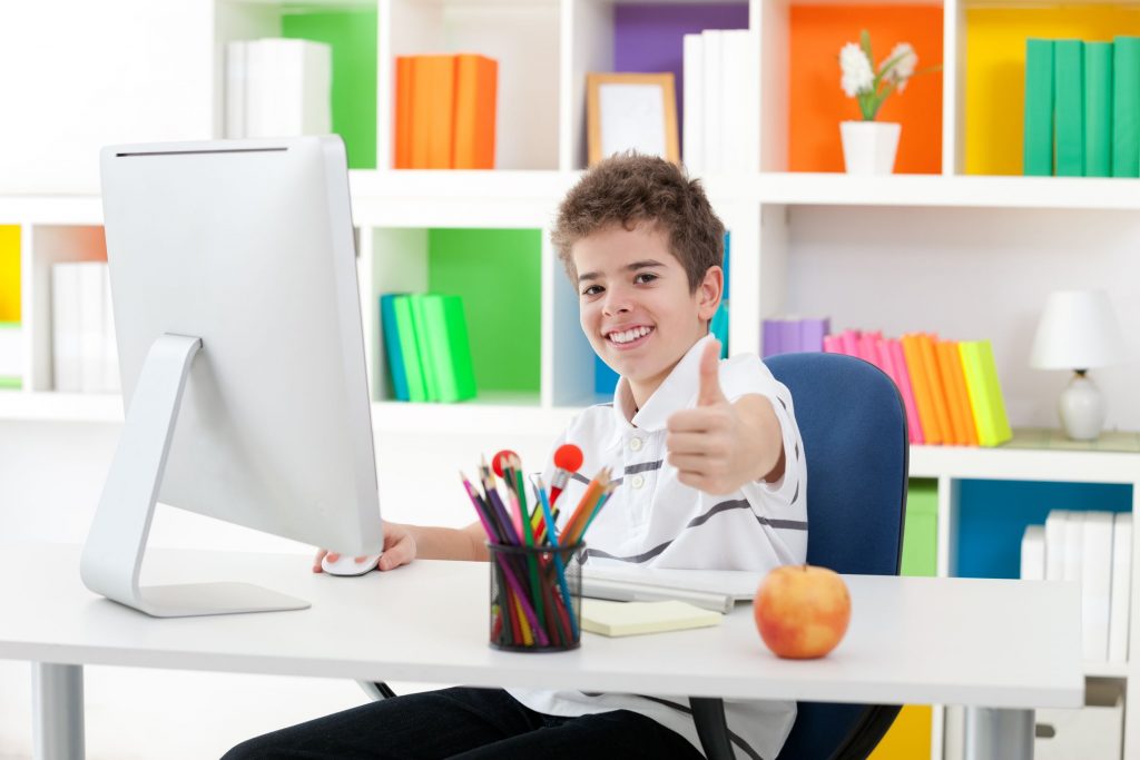 boy sitting front of computer and showing thumb up
