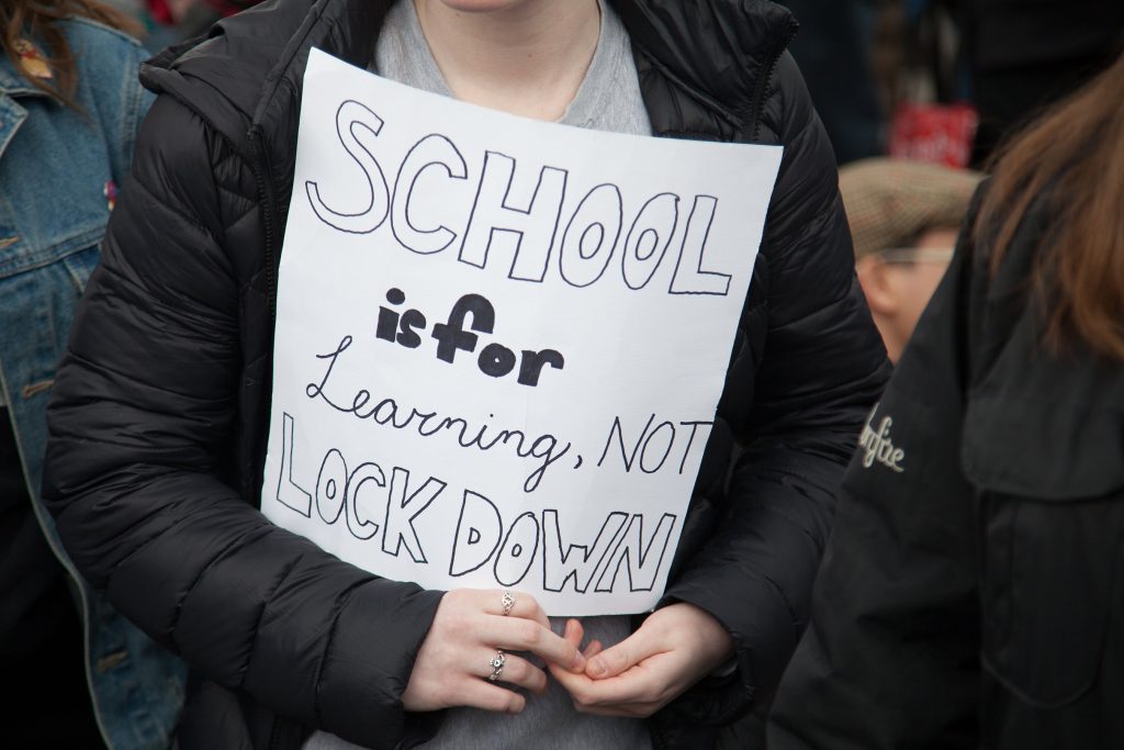 American Protesting Gun Violence Holds Sign that Reads, "School is for learning not lock down."
