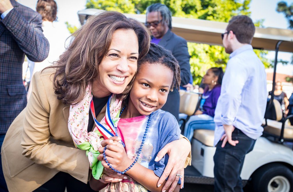 Kamala Harris poses with a young child at event.